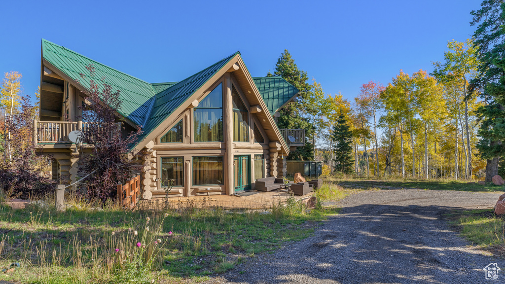 View of side of property featuring a patio, log exterior, metal roof, and a standing seam roof