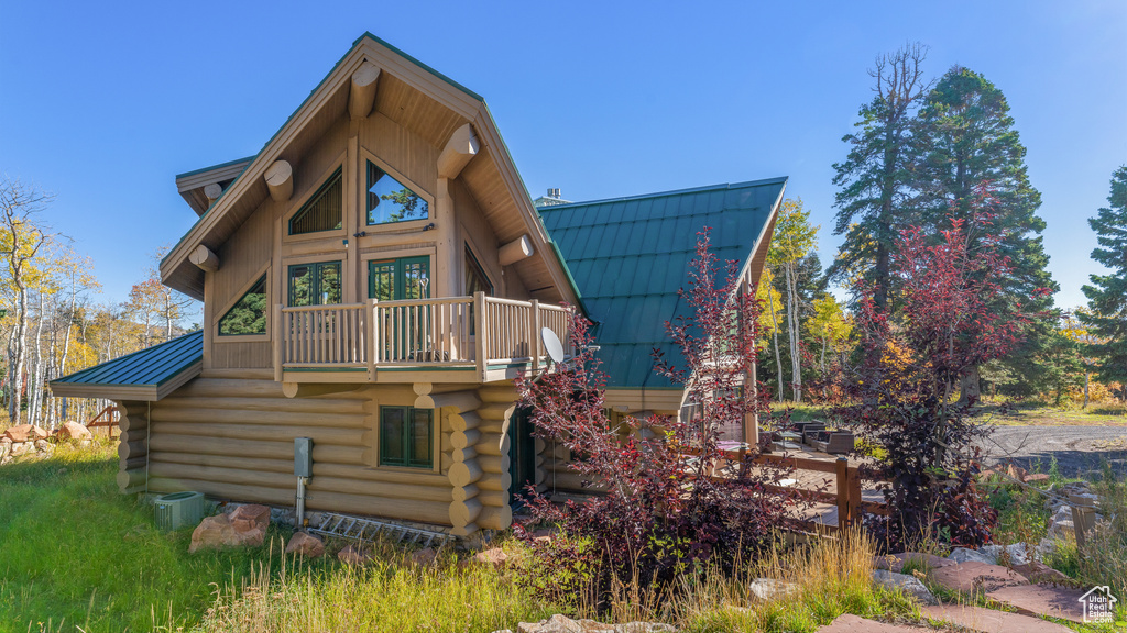 Rear view of house with log siding, metal roof, and a balcony