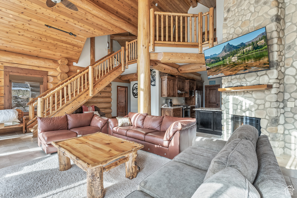 Living area featuring wooden ceiling, stairs, high vaulted ceiling, and rustic walls