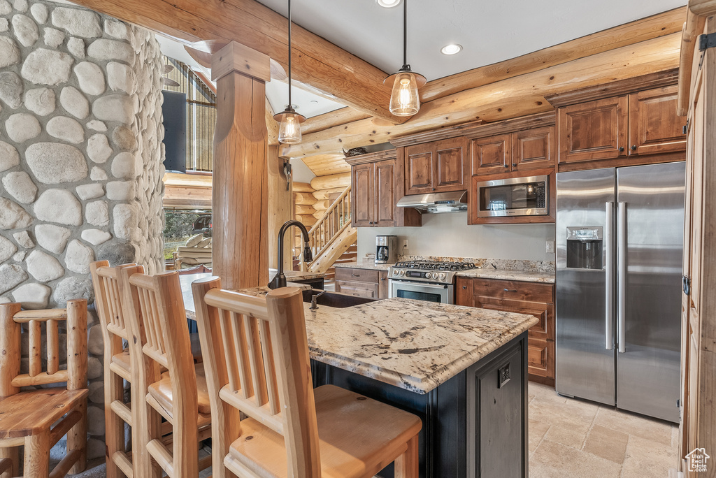 Kitchen featuring stainless steel appliances, a kitchen breakfast bar, recessed lighting, light stone countertops, and rustic walls