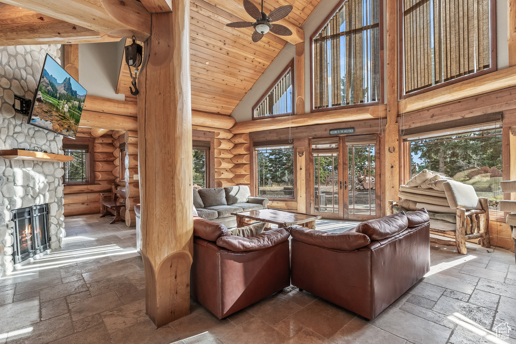 Living area featuring stone tile flooring, wood ceiling, a stone fireplace, and high vaulted ceiling