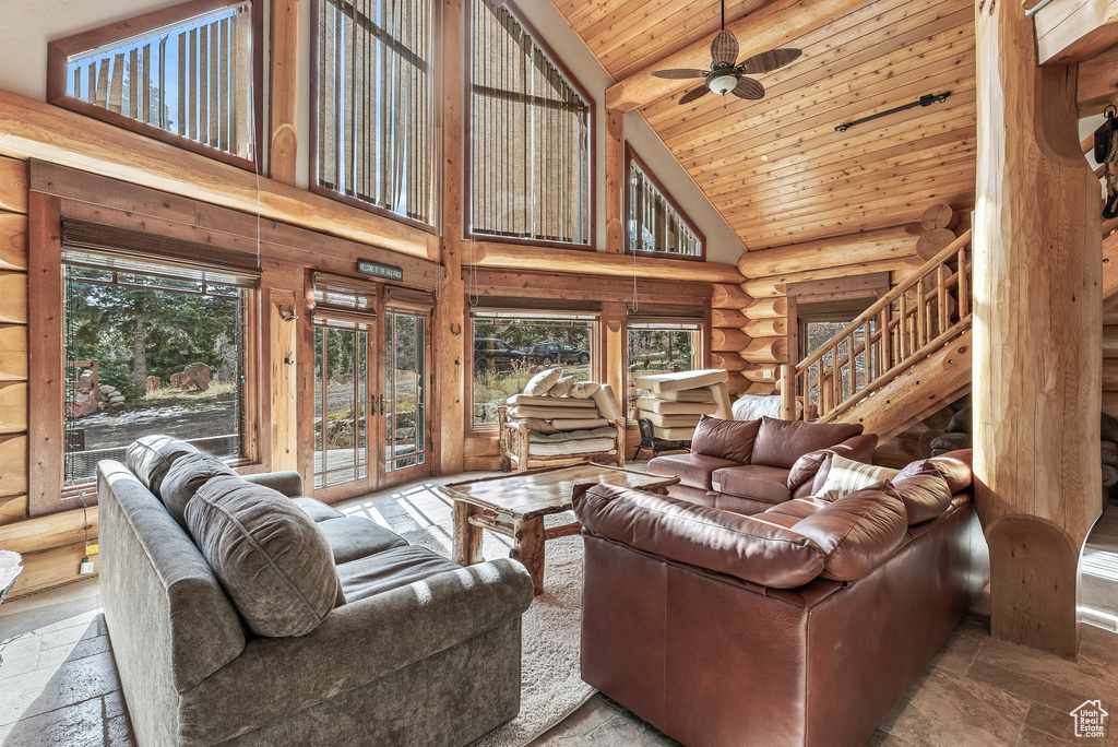 Living area featuring wood ceiling, rustic walls, a healthy amount of sunlight, and high vaulted ceiling