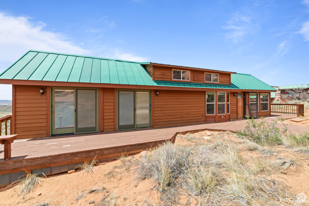 Back of property featuring a wooden deck and metal roof