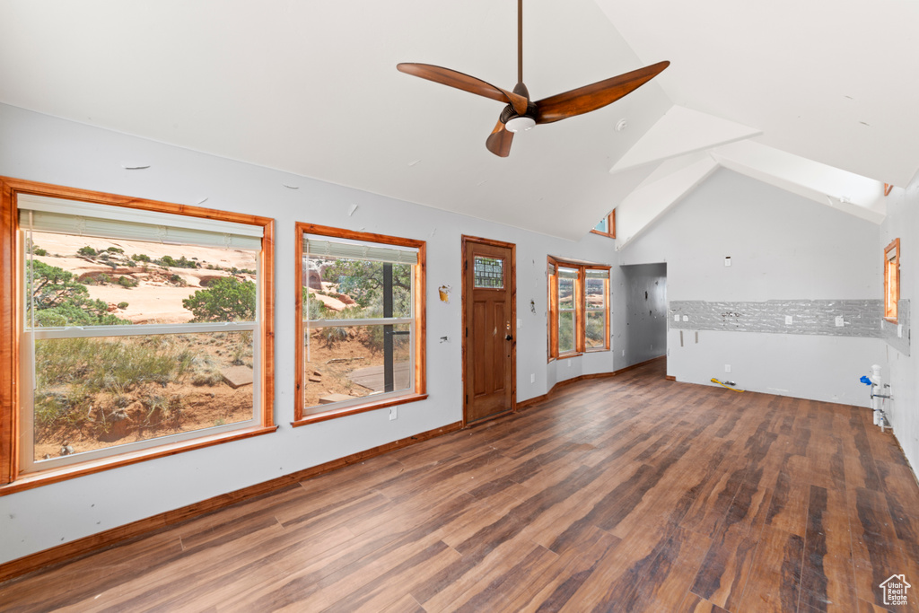 Unfurnished living room featuring wood finished floors, a ceiling fan, and vaulted ceiling