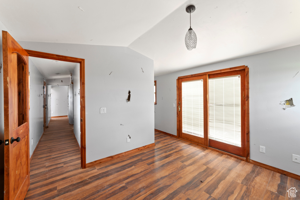 Empty room with wood finished floors, baseboards, and lofted ceiling