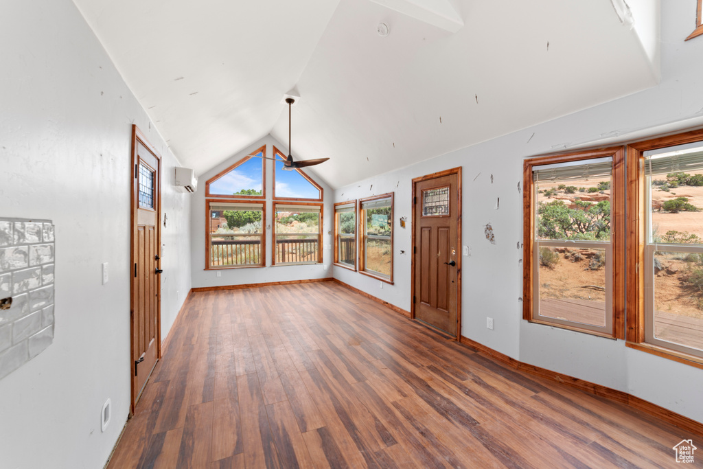 Unfurnished living room featuring lofted ceiling, wood finished floors, a ceiling fan, and baseboards
