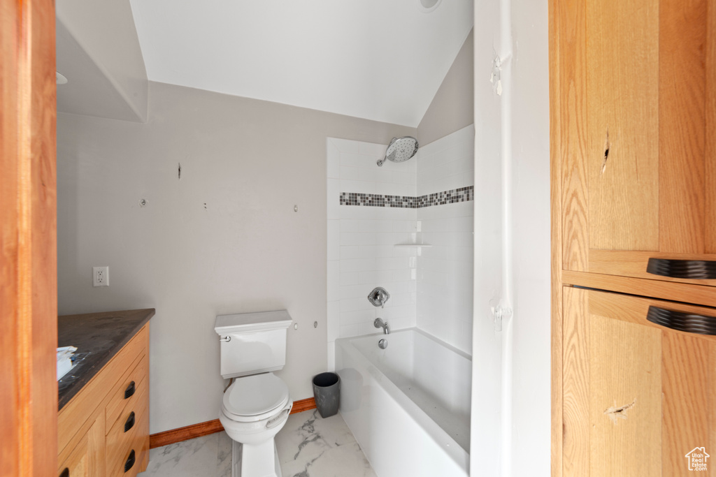 Bathroom with marble finish flooring, toilet, vanity, shower / washtub combination, and vaulted ceiling