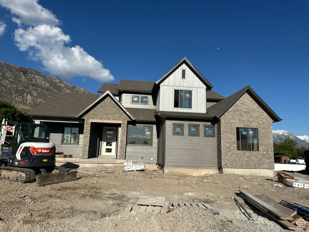 View of front facade with a mountain view, brick siding, and board and batten siding