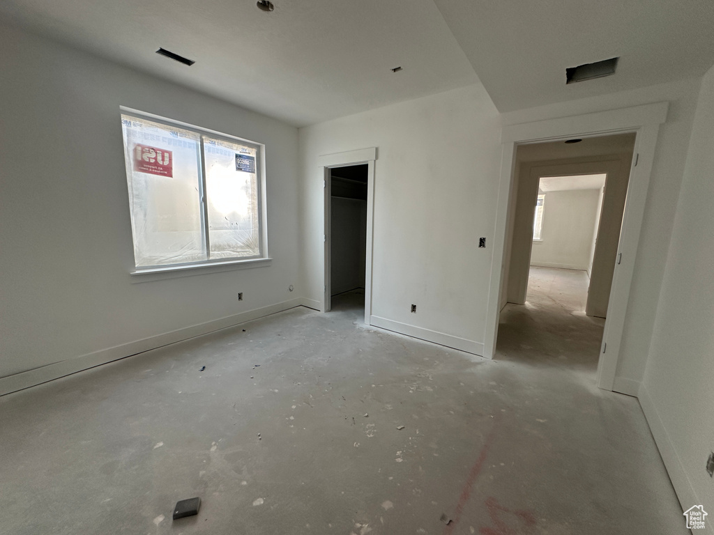 Unfurnished bedroom with multiple windows, unfinished concrete flooring, and baseboards