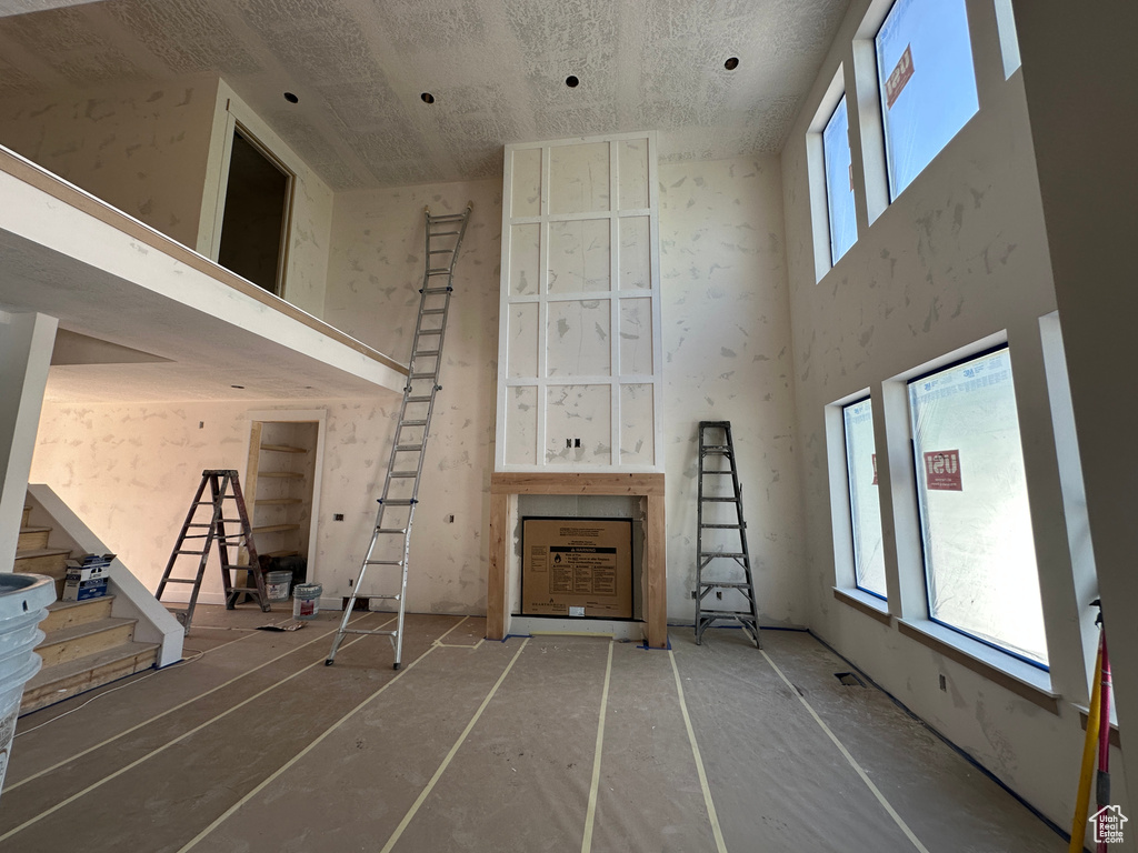 Unfurnished living room featuring a high ceiling and stairway