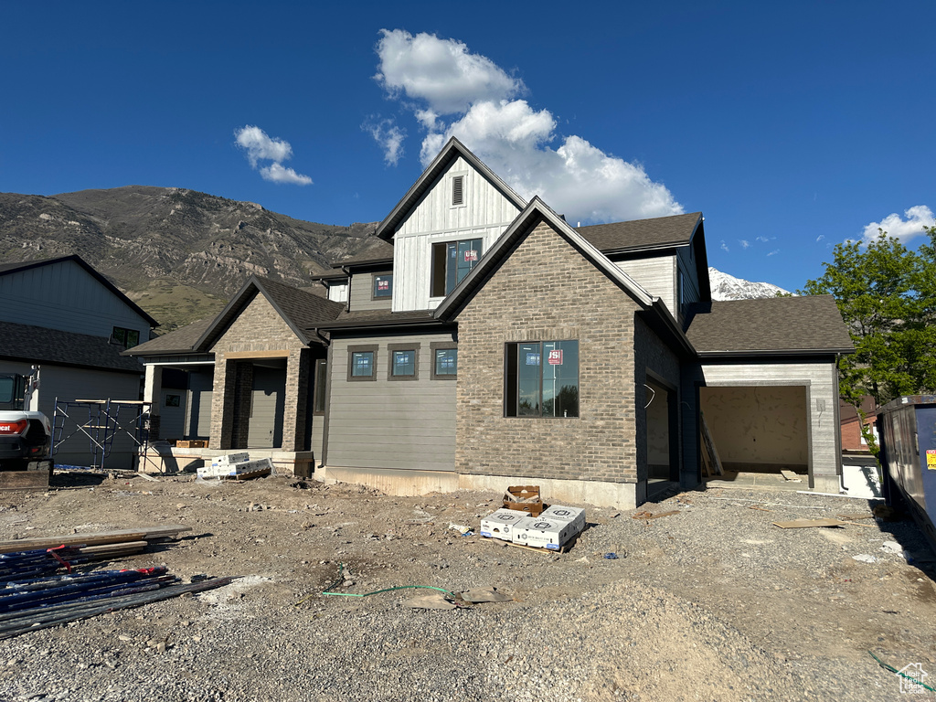 View of front of property featuring an attached garage, a mountain view, board and batten siding, and brick siding