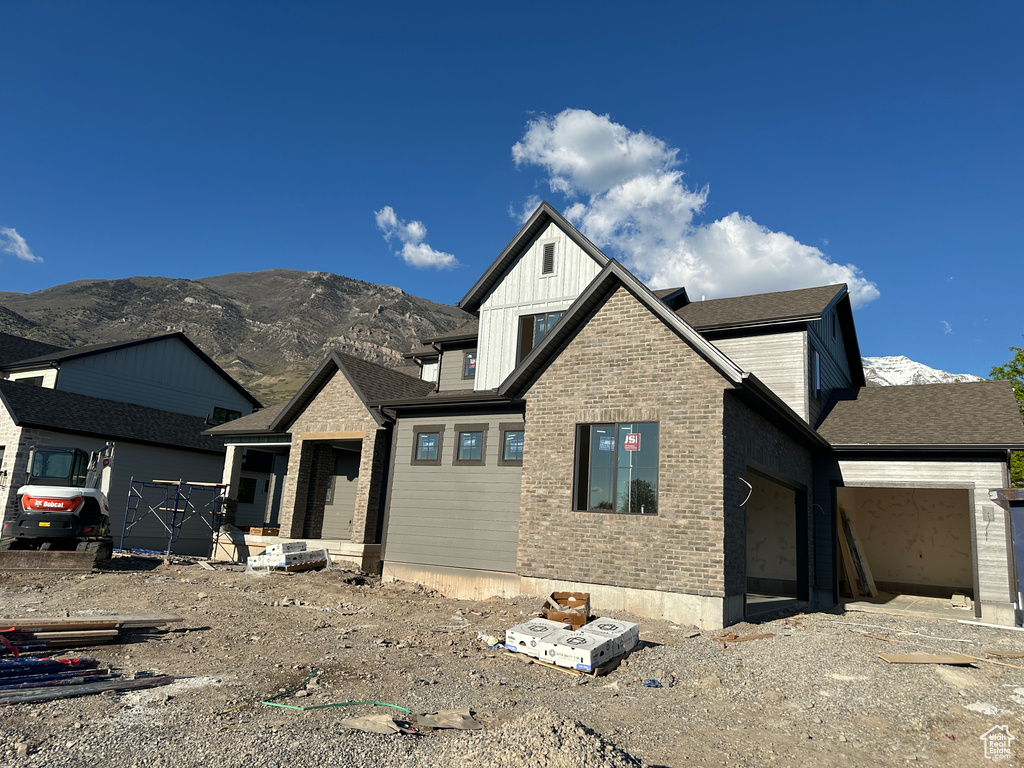 View of front facade with a mountain view, a garage, brick siding, and board and batten siding