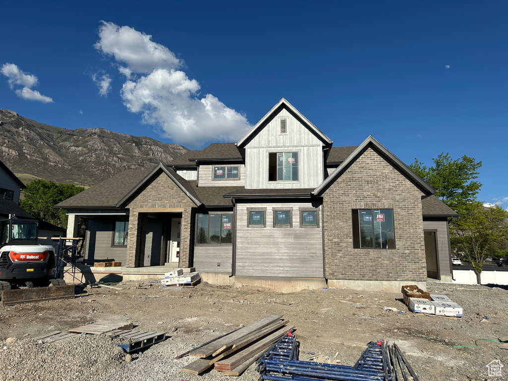 View of front facade with board and batten siding, a mountain view, and brick siding