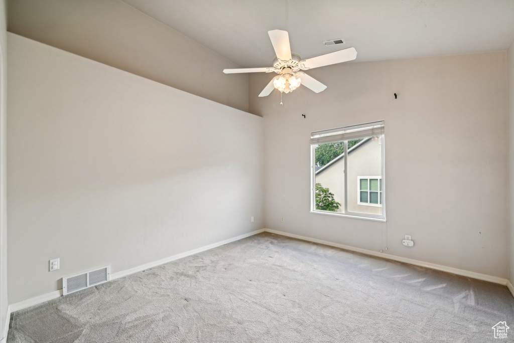 Carpeted spare room with baseboards, ceiling fan, and a high ceiling