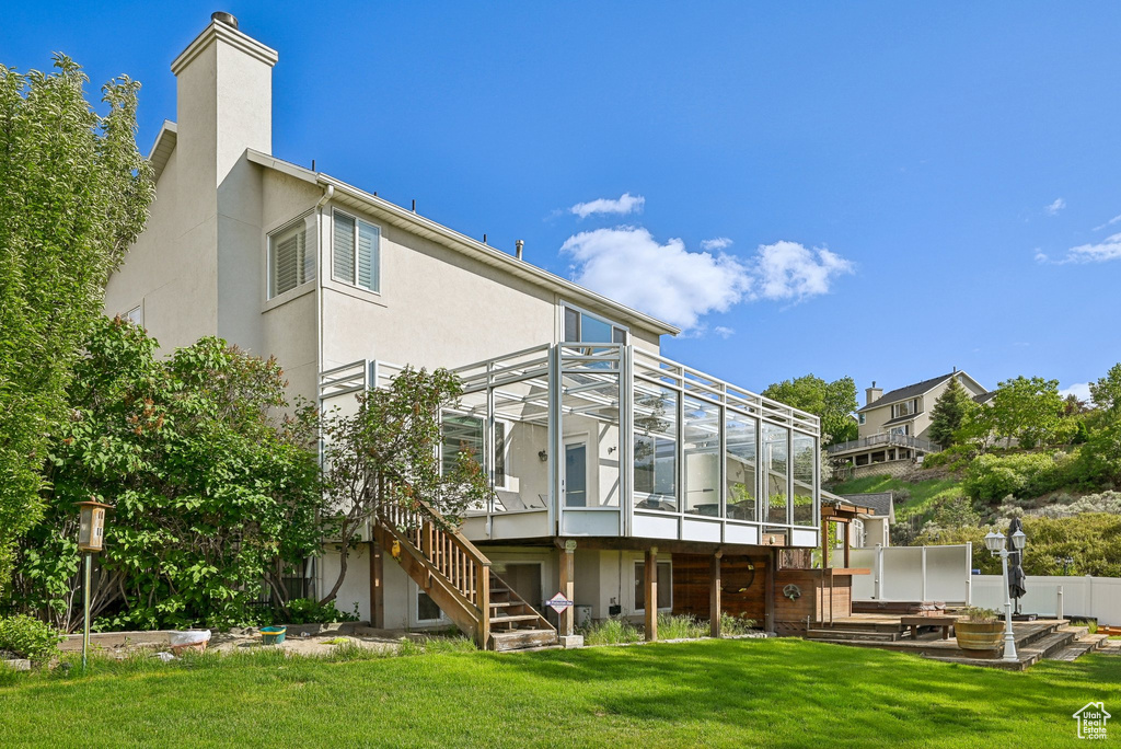 Back of house with stucco siding, stairs, a yard, and a deck