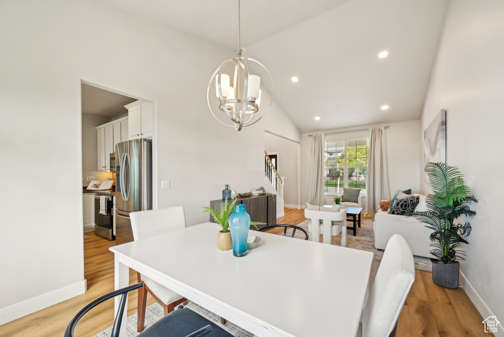 Dining area featuring a chandelier, baseboards, light wood-style flooring, vaulted ceiling, and recessed lighting