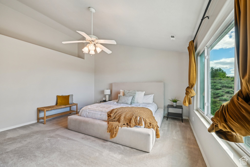 Carpeted bedroom featuring lofted ceiling, baseboards, and a ceiling fan