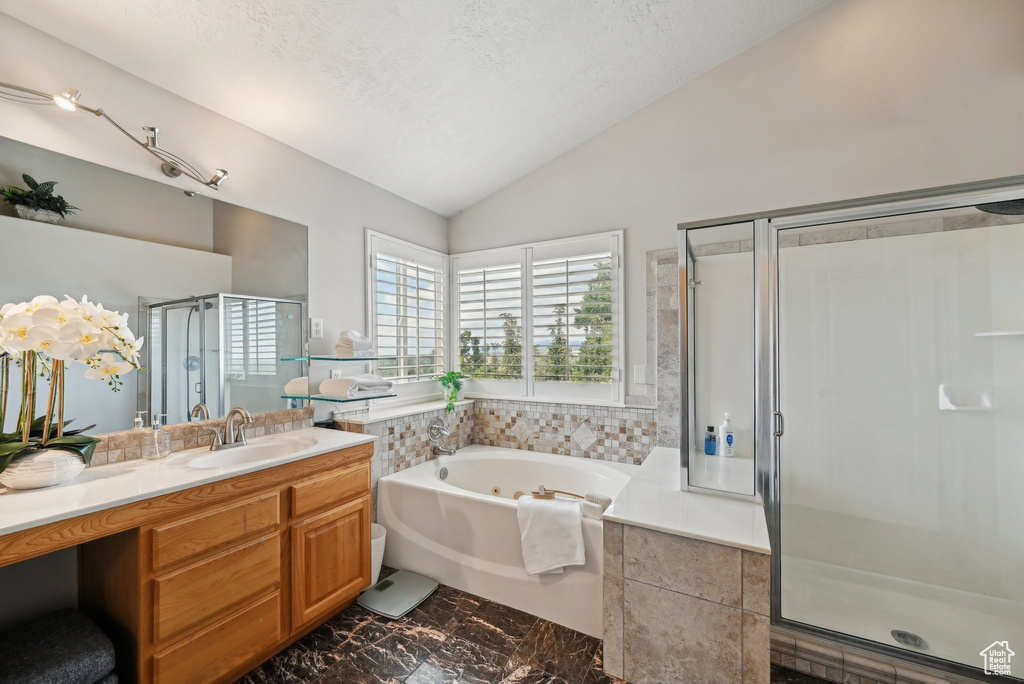 Full bath with lofted ceiling, a shower stall, a jetted tub, vanity, and marble finish floors