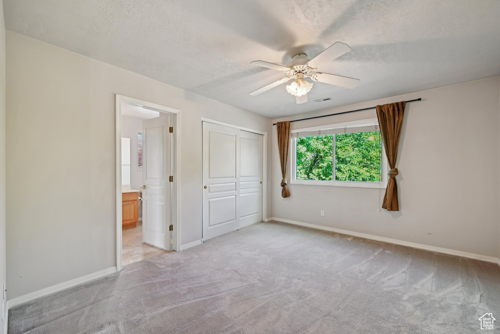 Unfurnished bedroom featuring light colored carpet, baseboards, and a textured ceiling