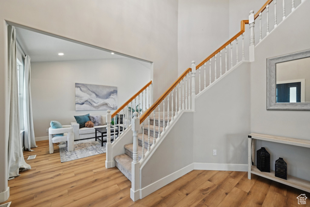 Stairway with wood finished floors, a high ceiling, baseboards, and recessed lighting
