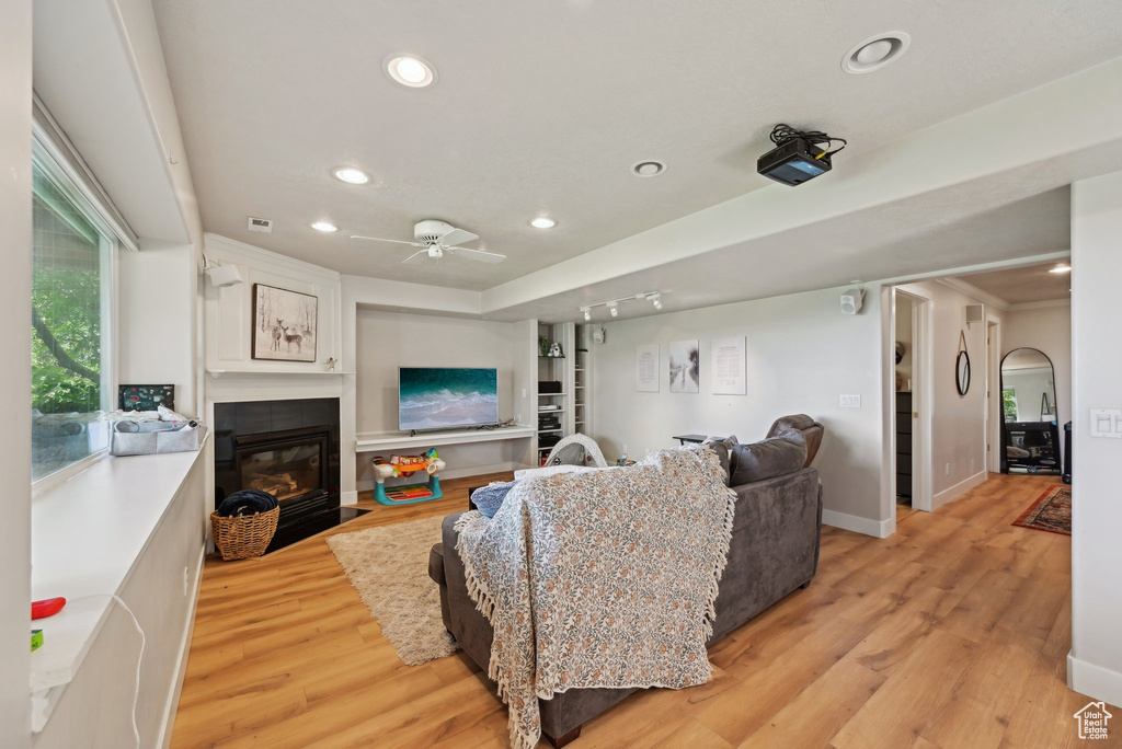 Living room with recessed lighting, light wood-type flooring, a fireplace with flush hearth, ceiling fan, and baseboards
