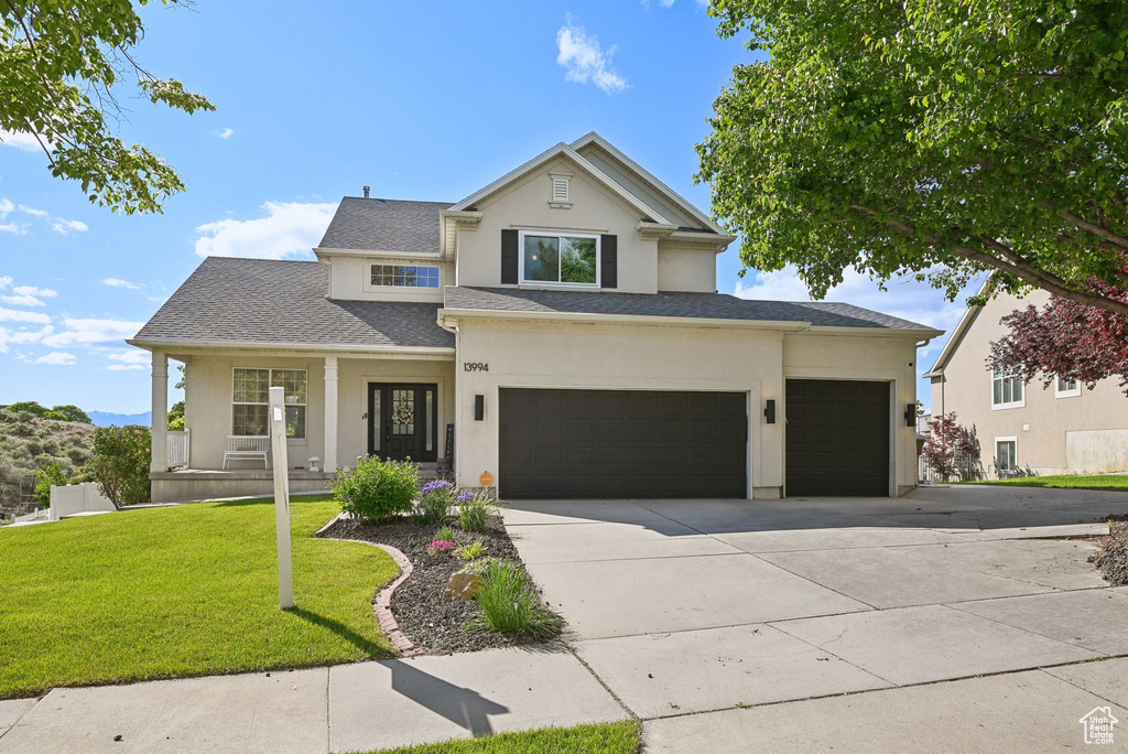 View of front of house featuring a porch, stucco siding, concrete driveway, a front lawn, and an attached garage