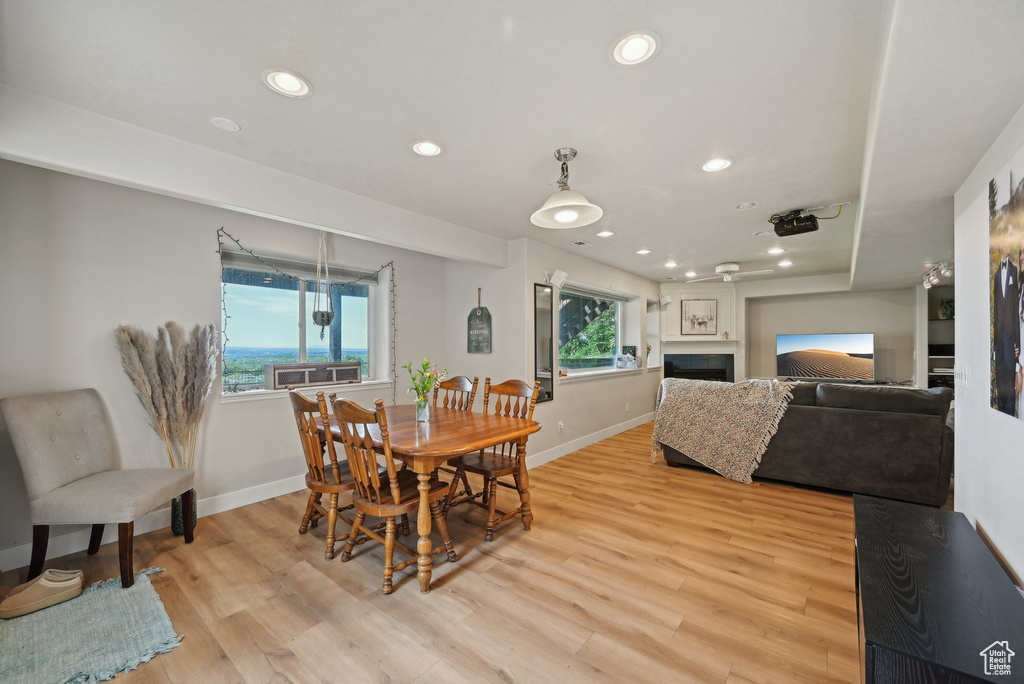 Dining area with baseboards, a fireplace, light wood-type flooring, and recessed lighting
