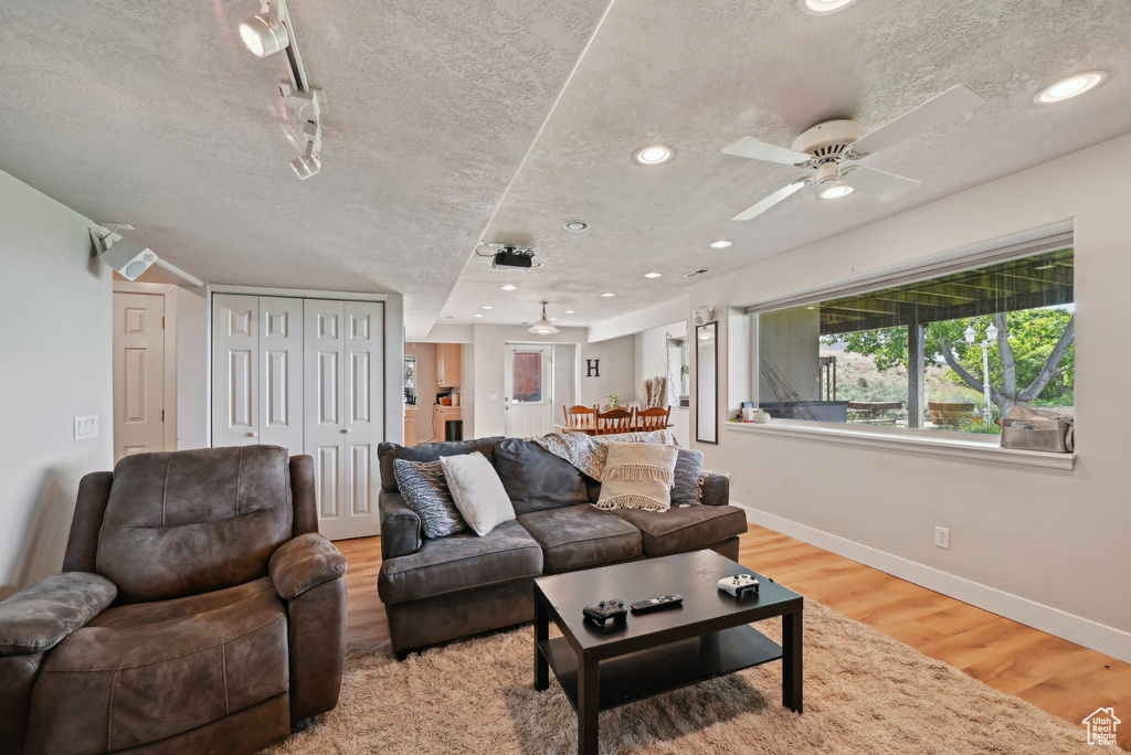 Living room featuring a textured ceiling, wood finished floors, baseboards, a ceiling fan, and recessed lighting
