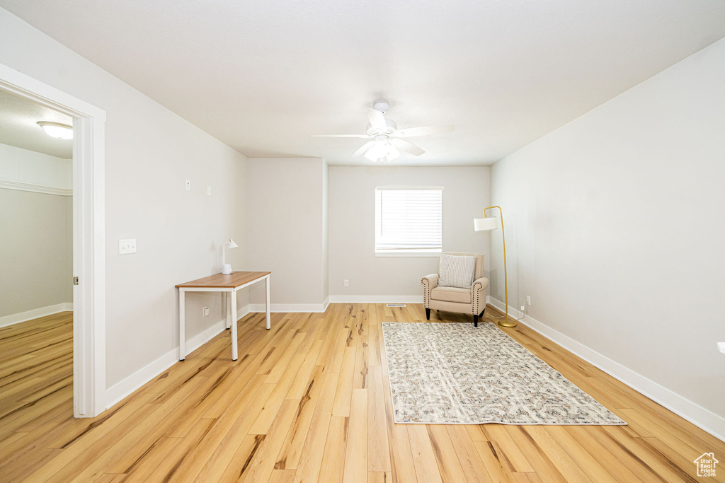 Living area featuring light wood finished floors, a ceiling fan, and baseboards