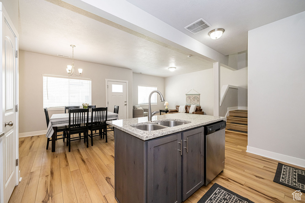 Kitchen with dishwasher, a sink, light wood-type flooring, and baseboards