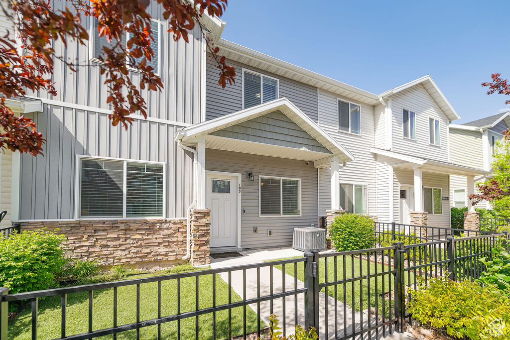 View of front of house featuring board and batten siding, central air condition unit, stone siding, and a porch
