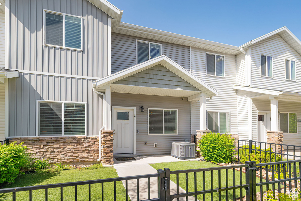 View of front of house with board and batten siding, central air condition unit, and stone siding