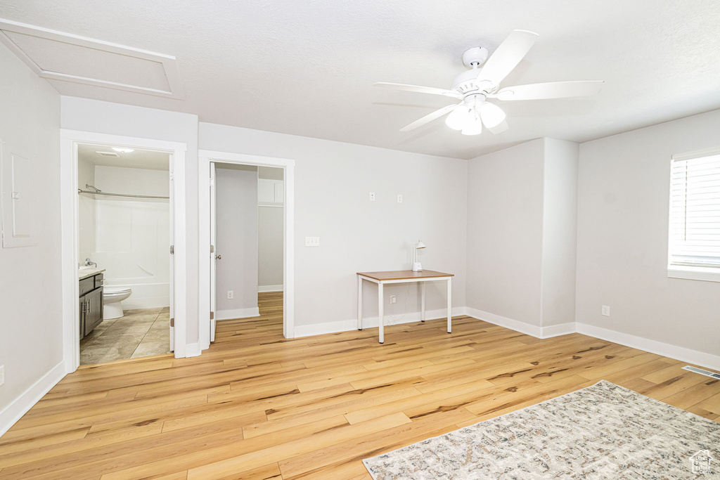 Unfurnished bedroom with light wood finished floors, attic access, baseboards, and connected bathroom