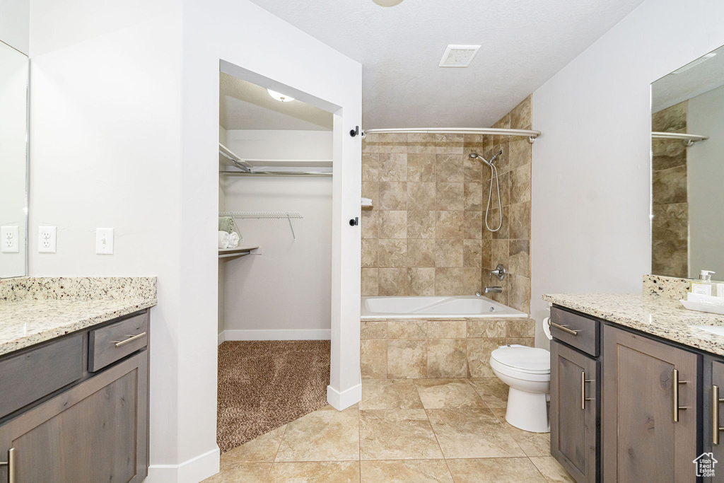 Full bath featuring vanity, baseboards, toilet, a walk in closet, and tiled shower / bath combo
