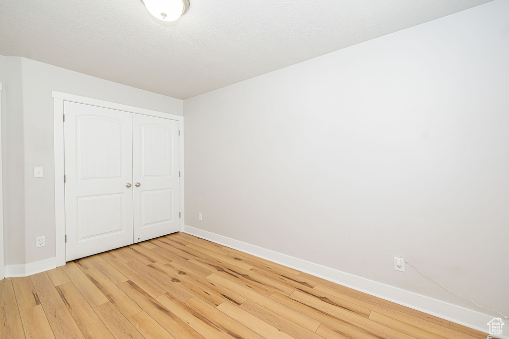 Unfurnished bedroom featuring light wood-style floors, baseboards, and a closet