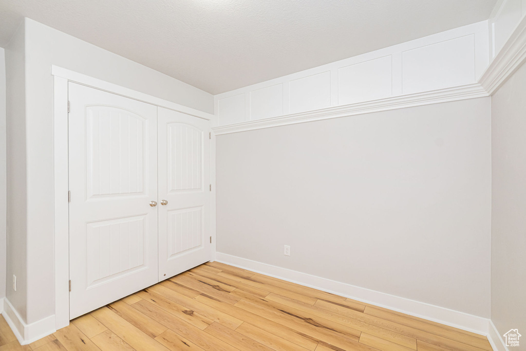 Unfurnished bedroom with light wood-style floors, baseboards, and a closet