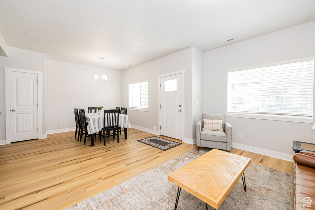 Living area with a chandelier, light wood-style floors, and baseboards