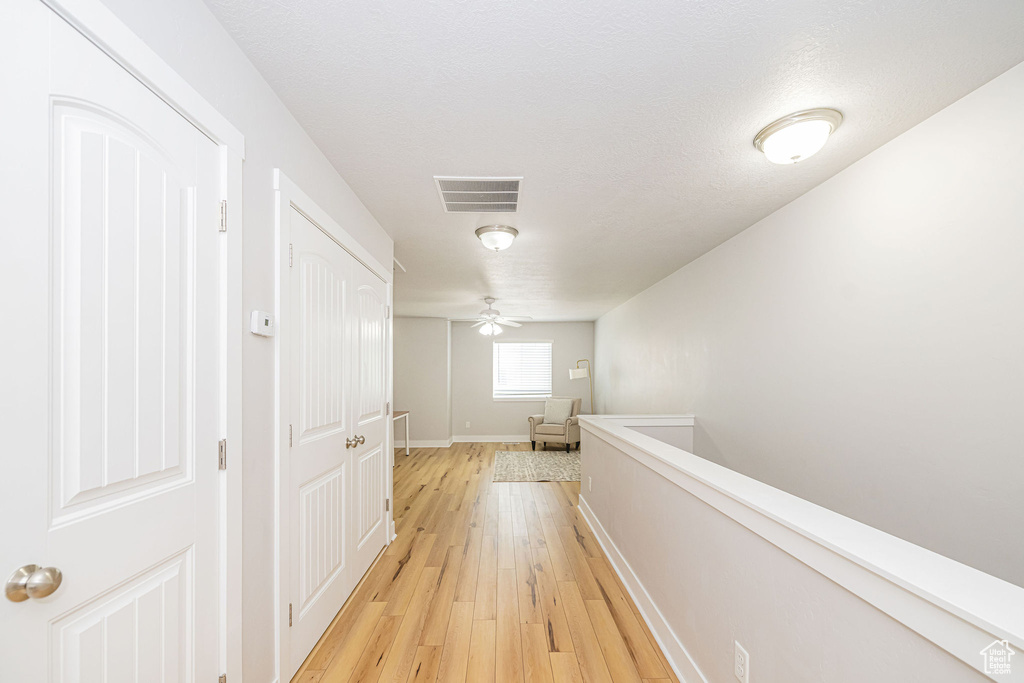 Corridor featuring light wood-style flooring and baseboards