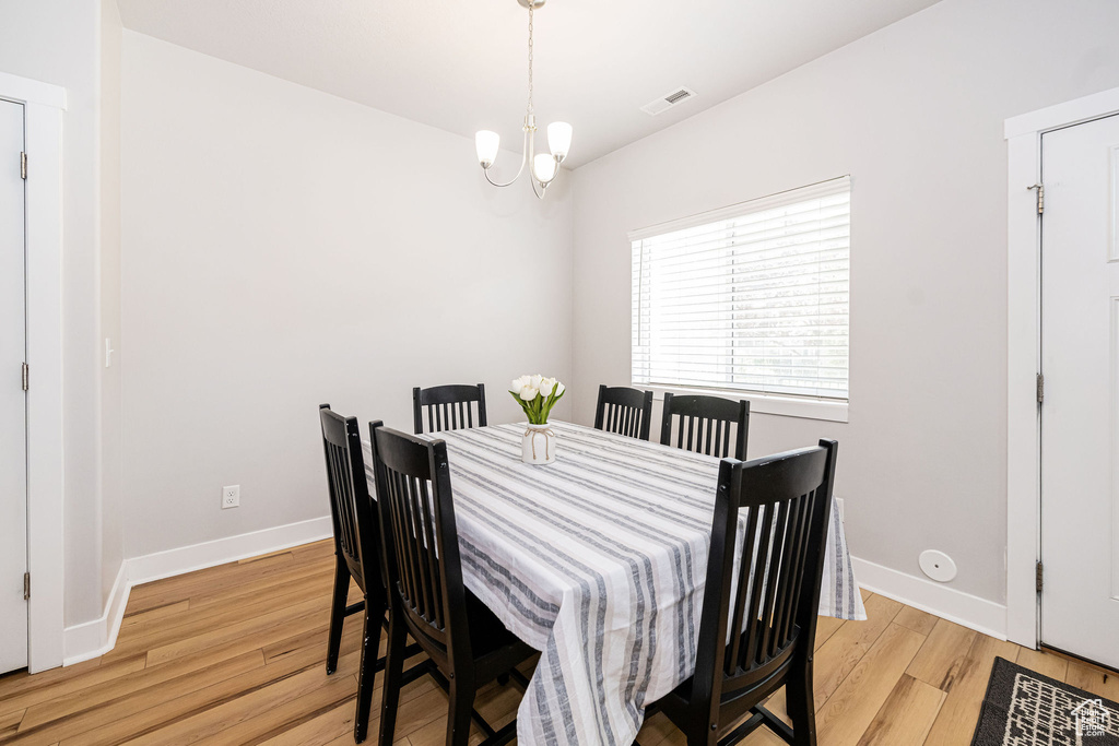 Dining space with light wood finished floors, a chandelier, and baseboards