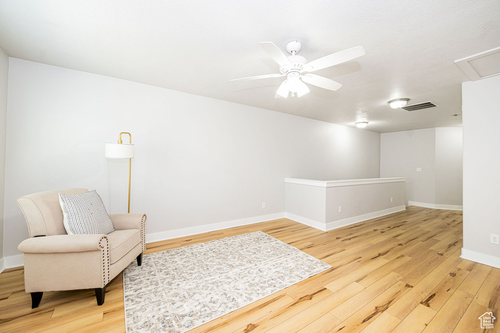 Living area featuring light wood-style flooring, ceiling fan, and baseboards