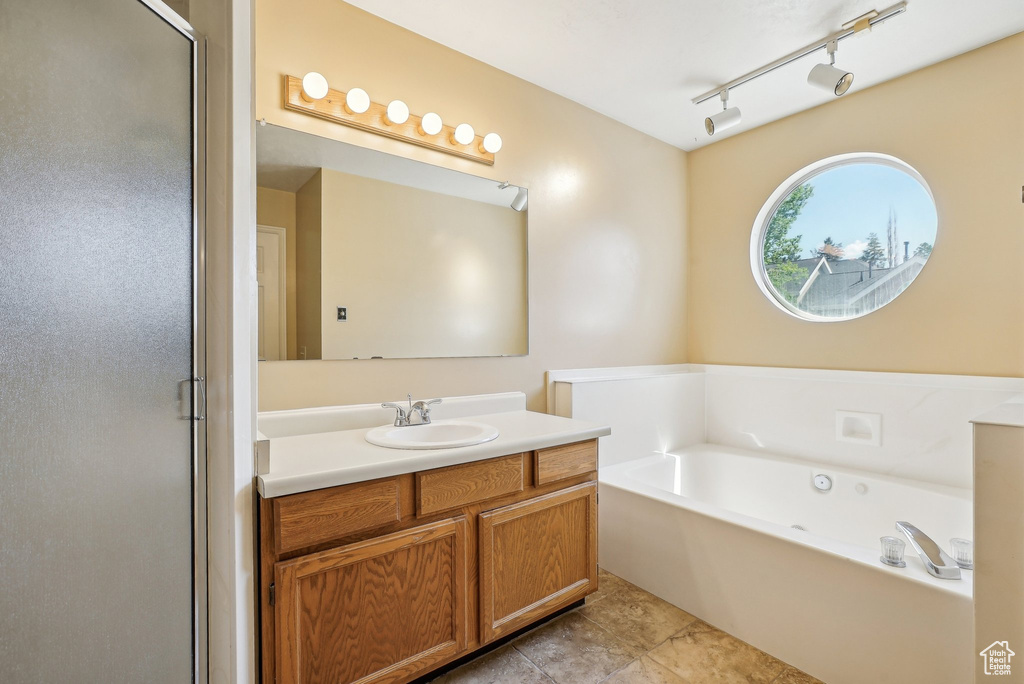 Bathroom featuring a garden tub, vanity, a shower stall, and tile patterned flooring