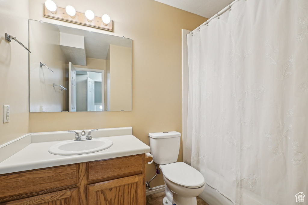 Full bathroom with toilet, vanity, and a shower with shower curtain