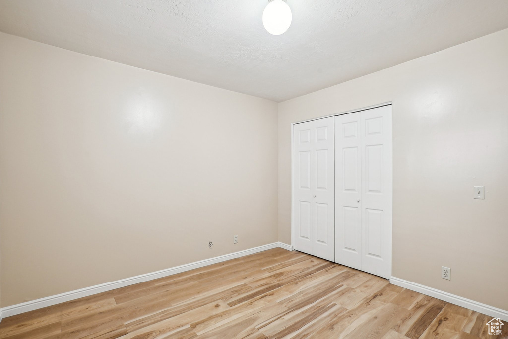 Unfurnished bedroom with light wood finished floors, baseboards, and a closet