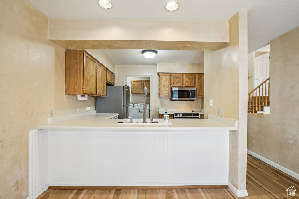 Kitchen featuring appliances with stainless steel finishes, a peninsula, and brown cabinets