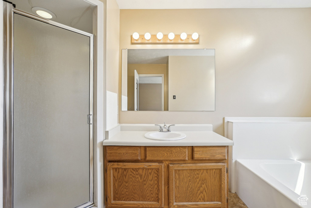 Bathroom featuring a bath, a stall shower, and vanity