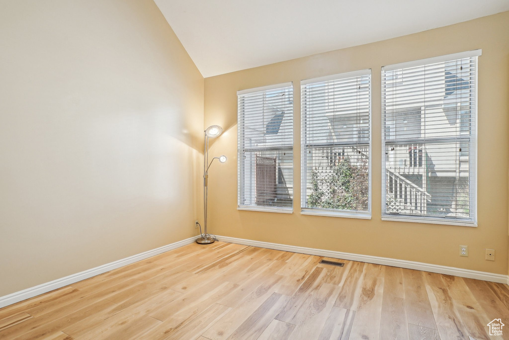Empty room featuring baseboards, wood finished floors, and lofted ceiling