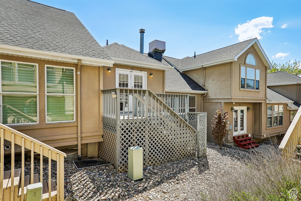 Rear view of house featuring stairway, roof with shingles, french doors, and stucco siding
