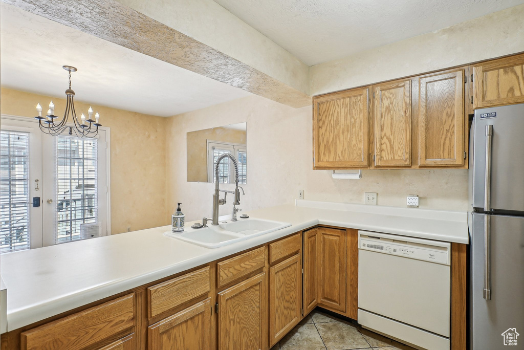 Kitchen with dishwasher, freestanding refrigerator, a sink, and plenty of natural light