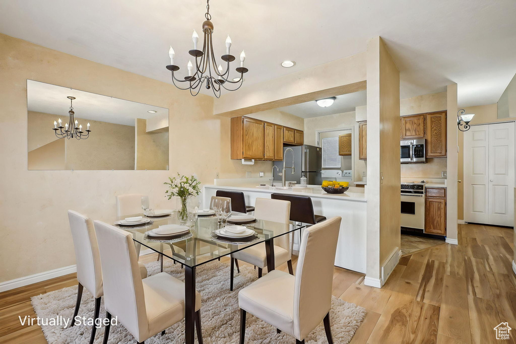Dining room featuring a chandelier, light wood-type flooring, baseboards, and recessed lighting