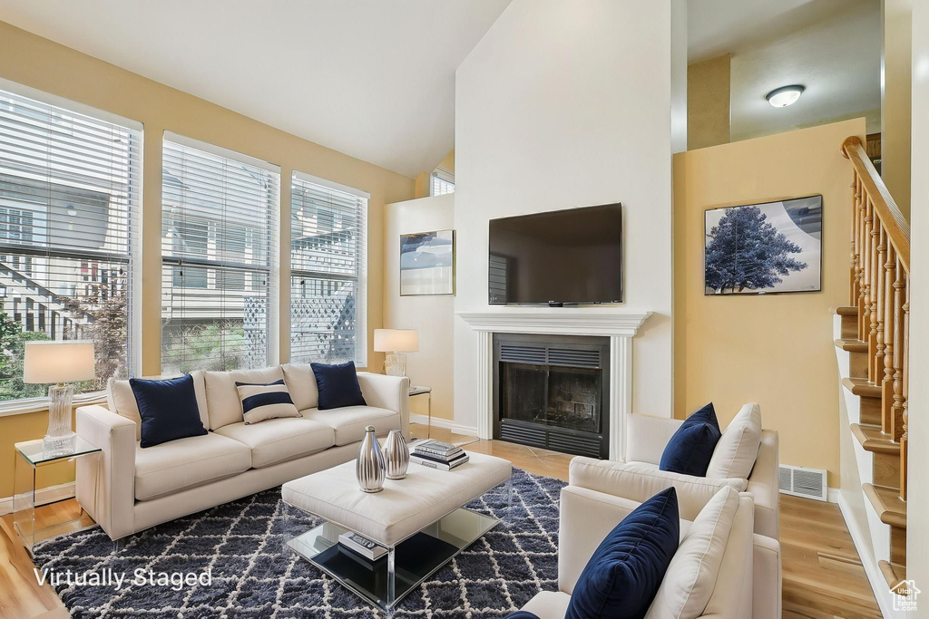 Living area featuring healthy amount of natural light, baseboards, wood finished floors, and lofted ceiling